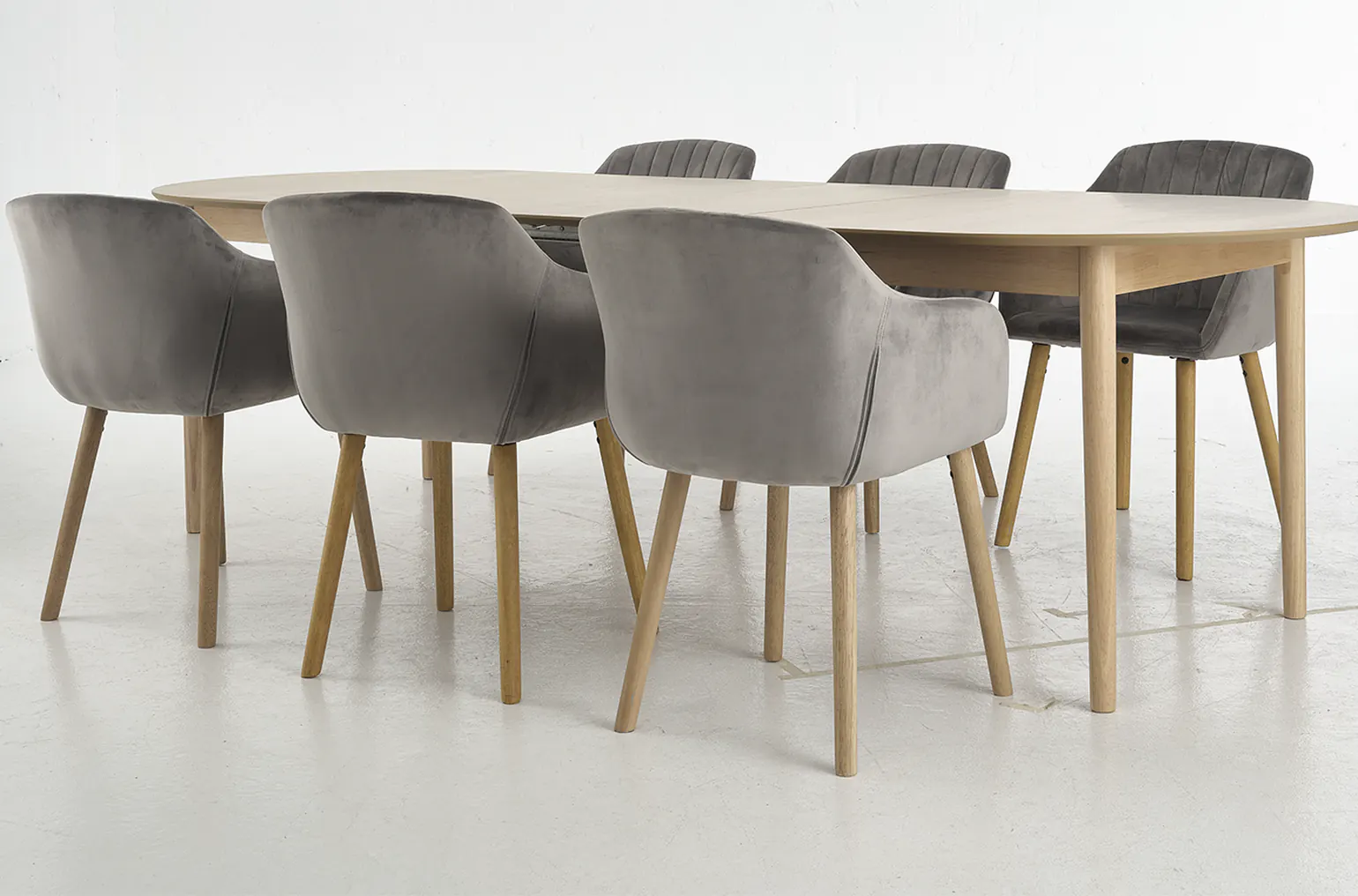 A dining table and chairs on a grey studio floor