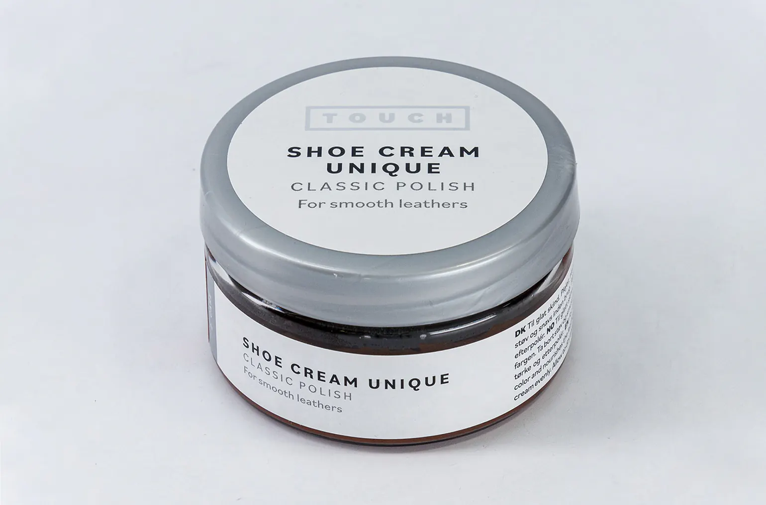 A tin of shoe cream on a grey studio background