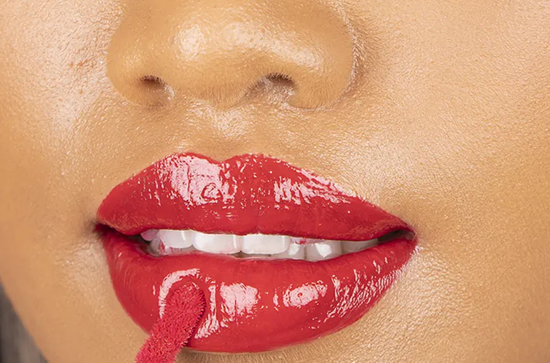 A close-up of glossy red lips before retouching